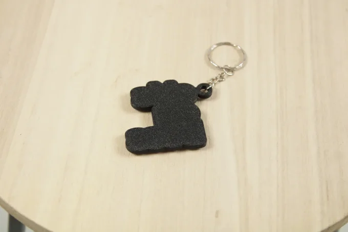Détail du porte-clés imprimé en 3D avec lettres blanches en relief sur base noire