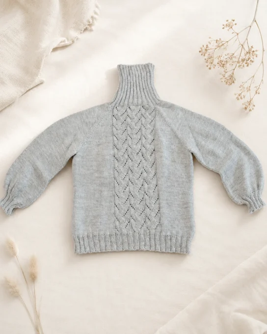 Mise en situation IA du pull col roulé gris vu à plat de face avec motif torsadé central
