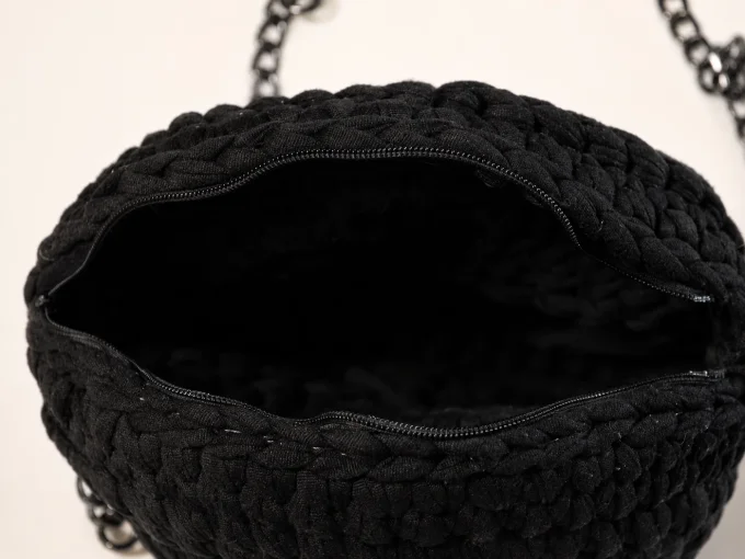 Ouverture du sac rond noir au crochet montrant la fermeture zippée et l’intérieur.