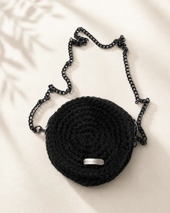 Mise en situation du sac rond noir au crochet porté en bandoulière.